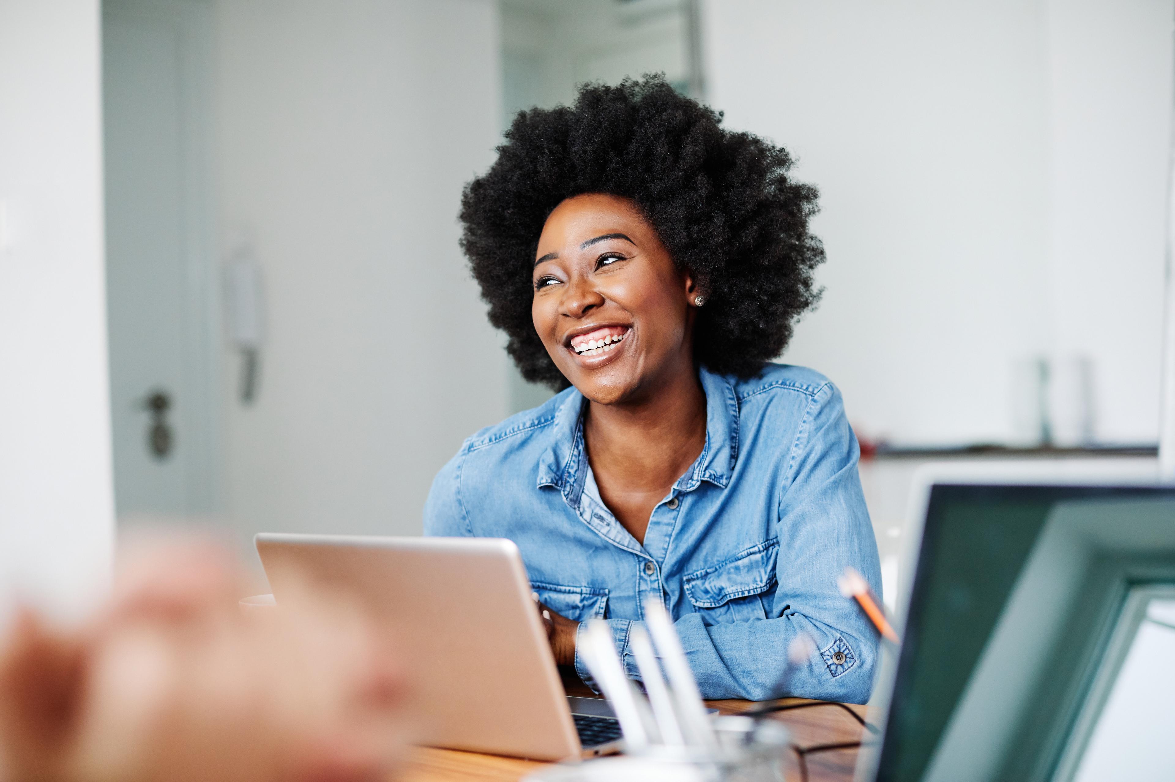 Woman laughing on her computer at home