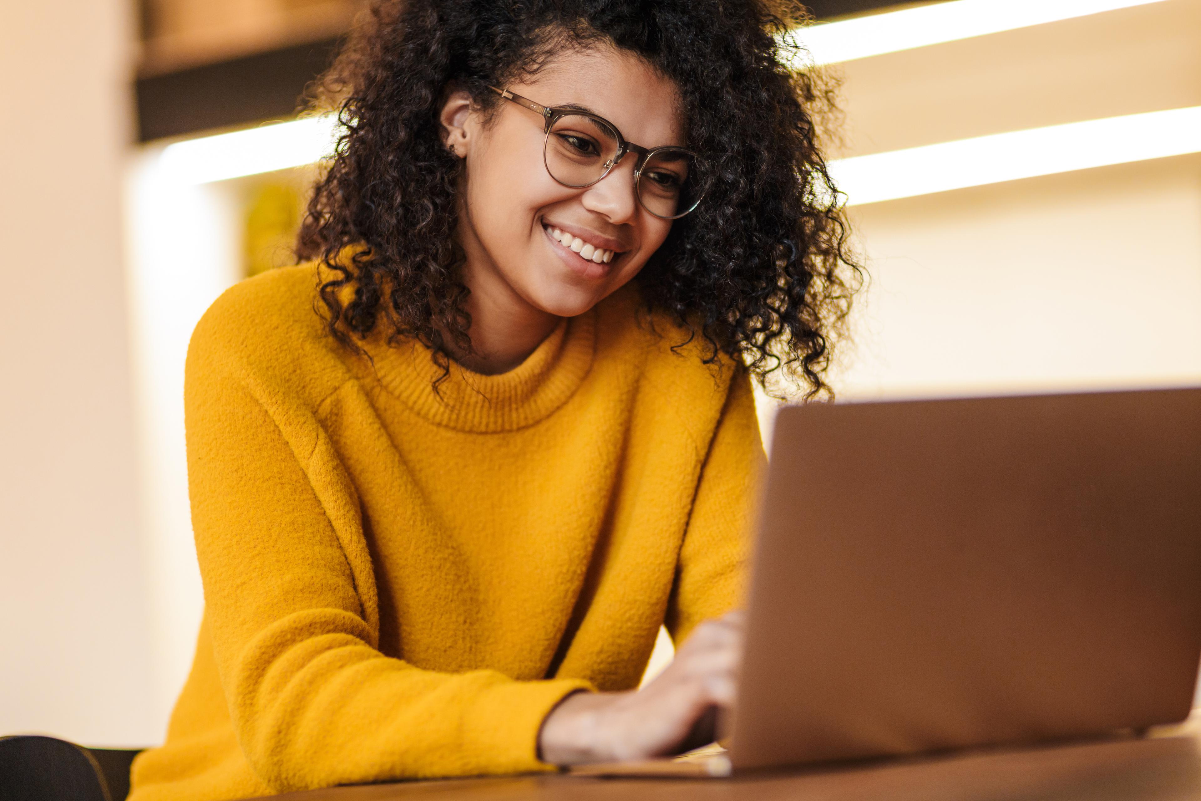 smiling woman with glasses working at laptop