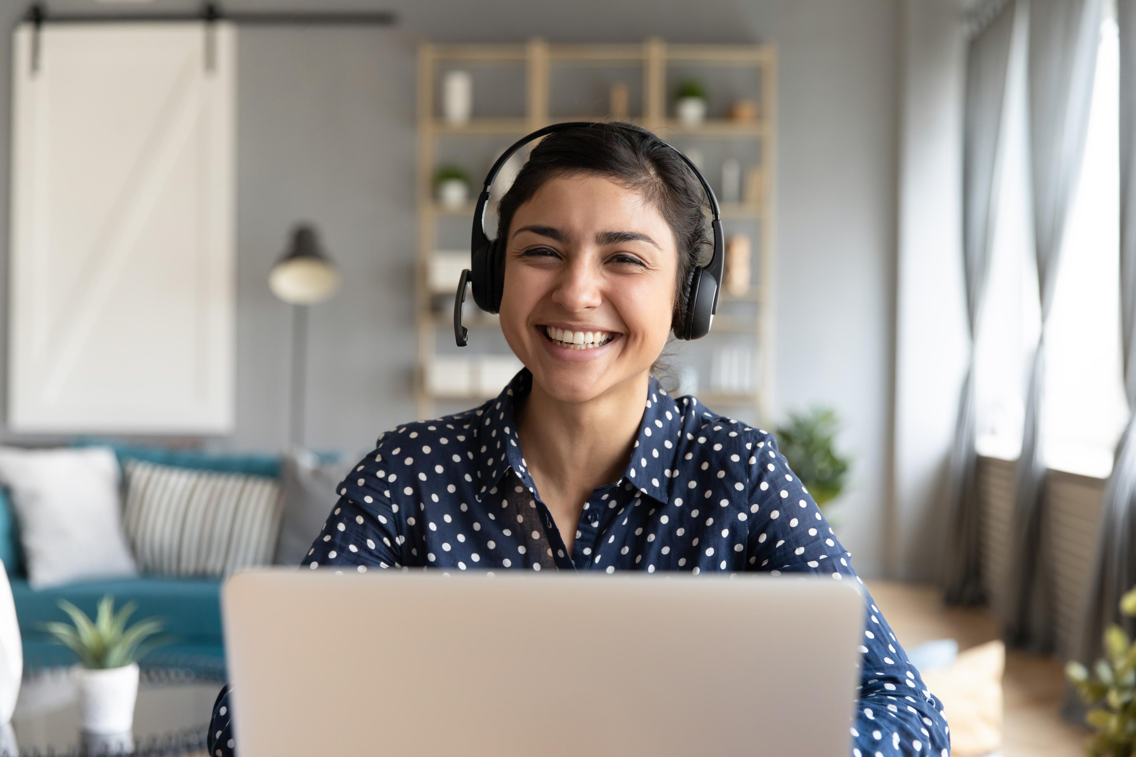 woman in headphones smiling at laptop