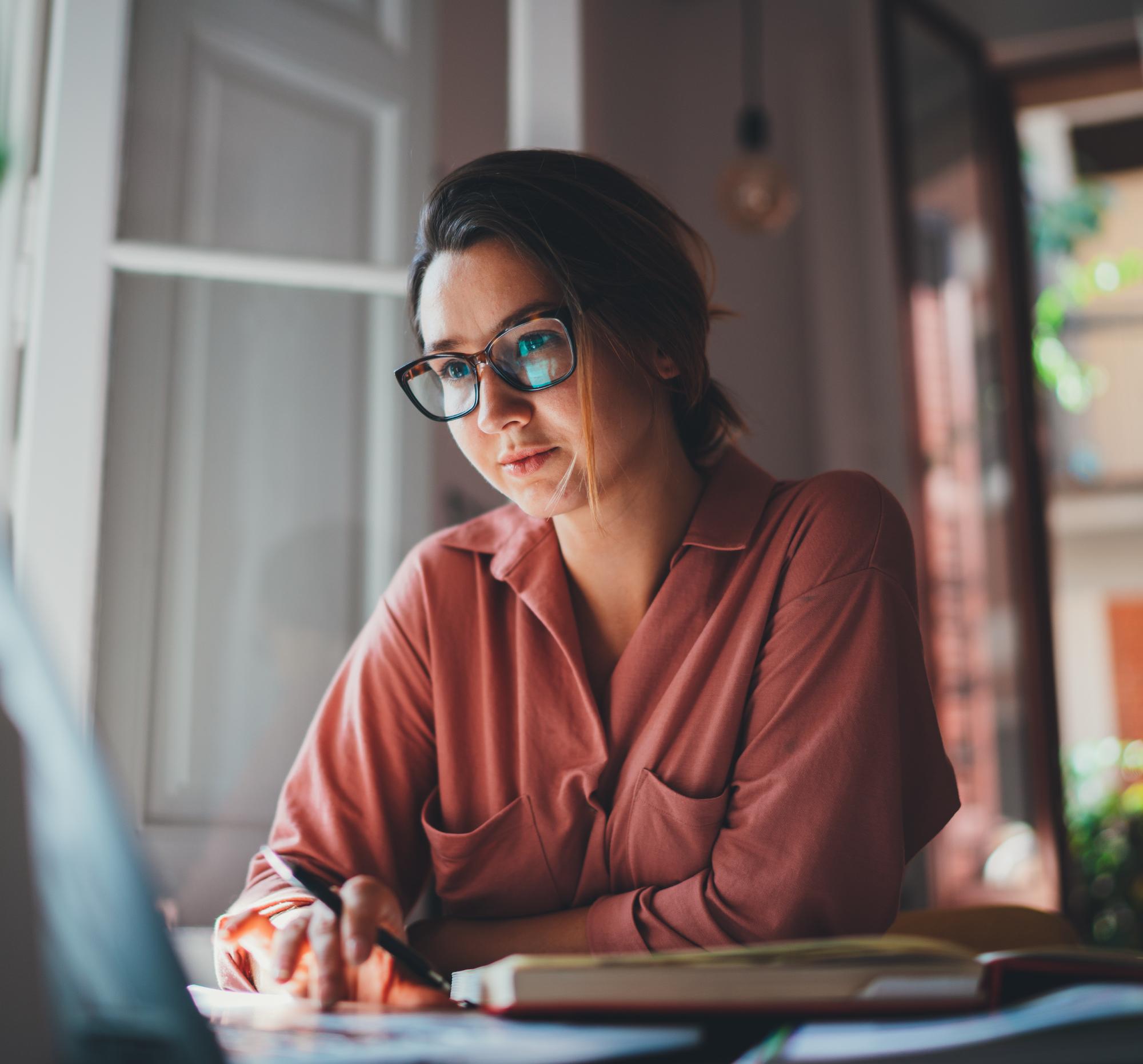 woman with glasses working at laptop