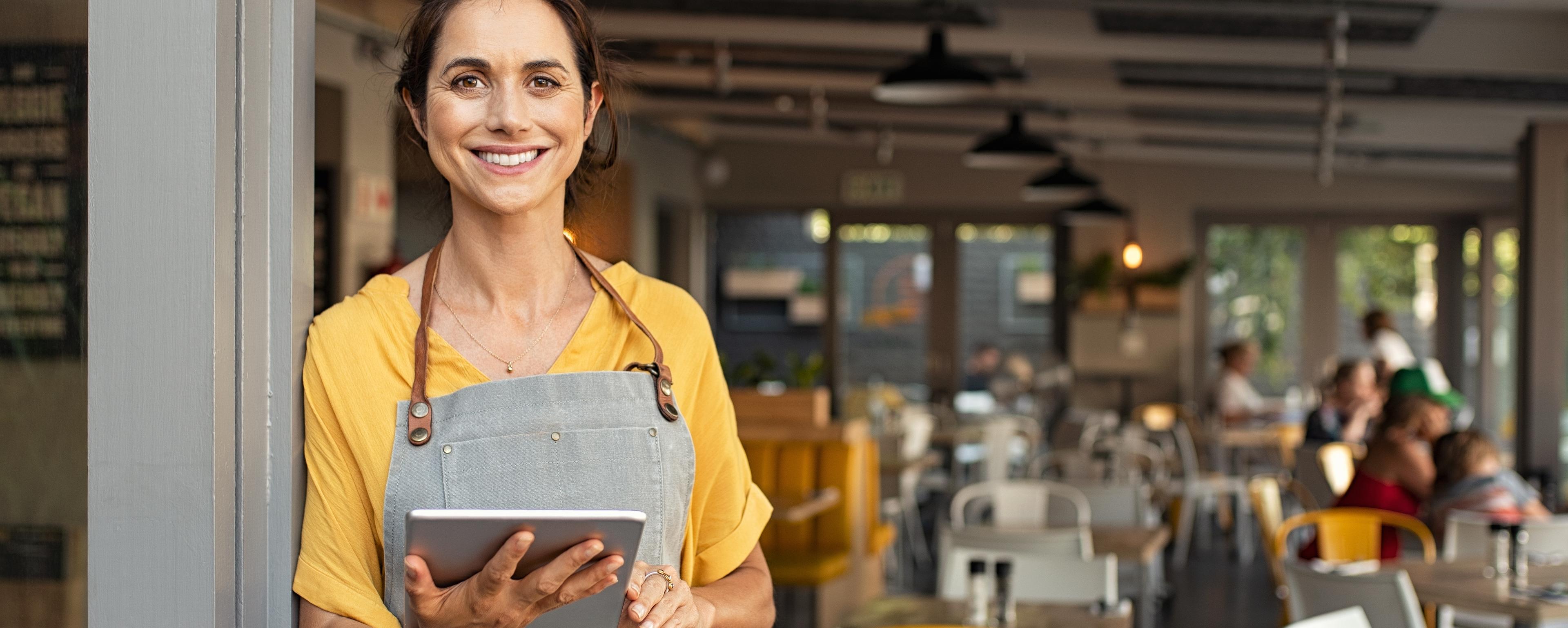 small business owner holding ipad standing in front of store