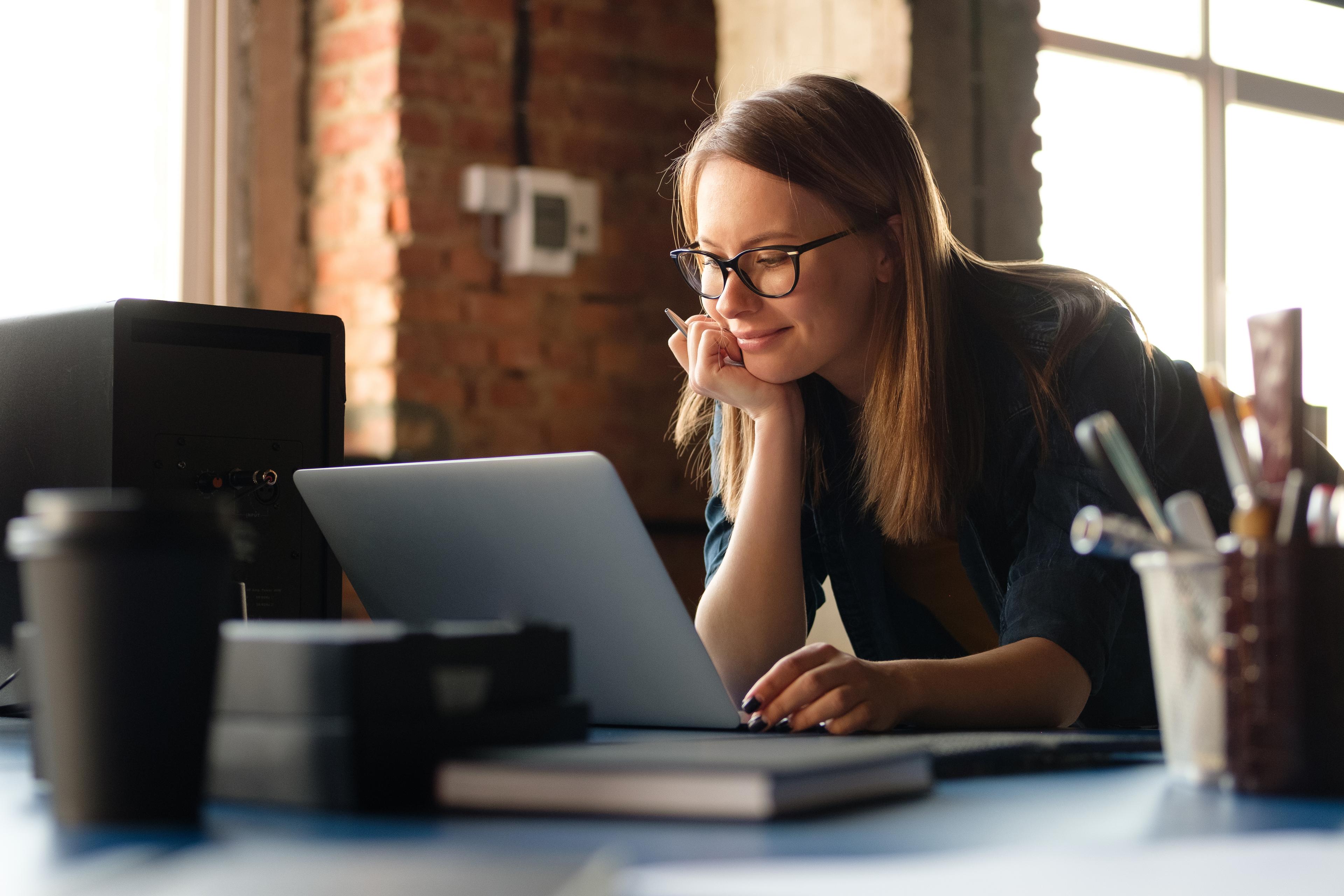 woman with glasses working at laptop