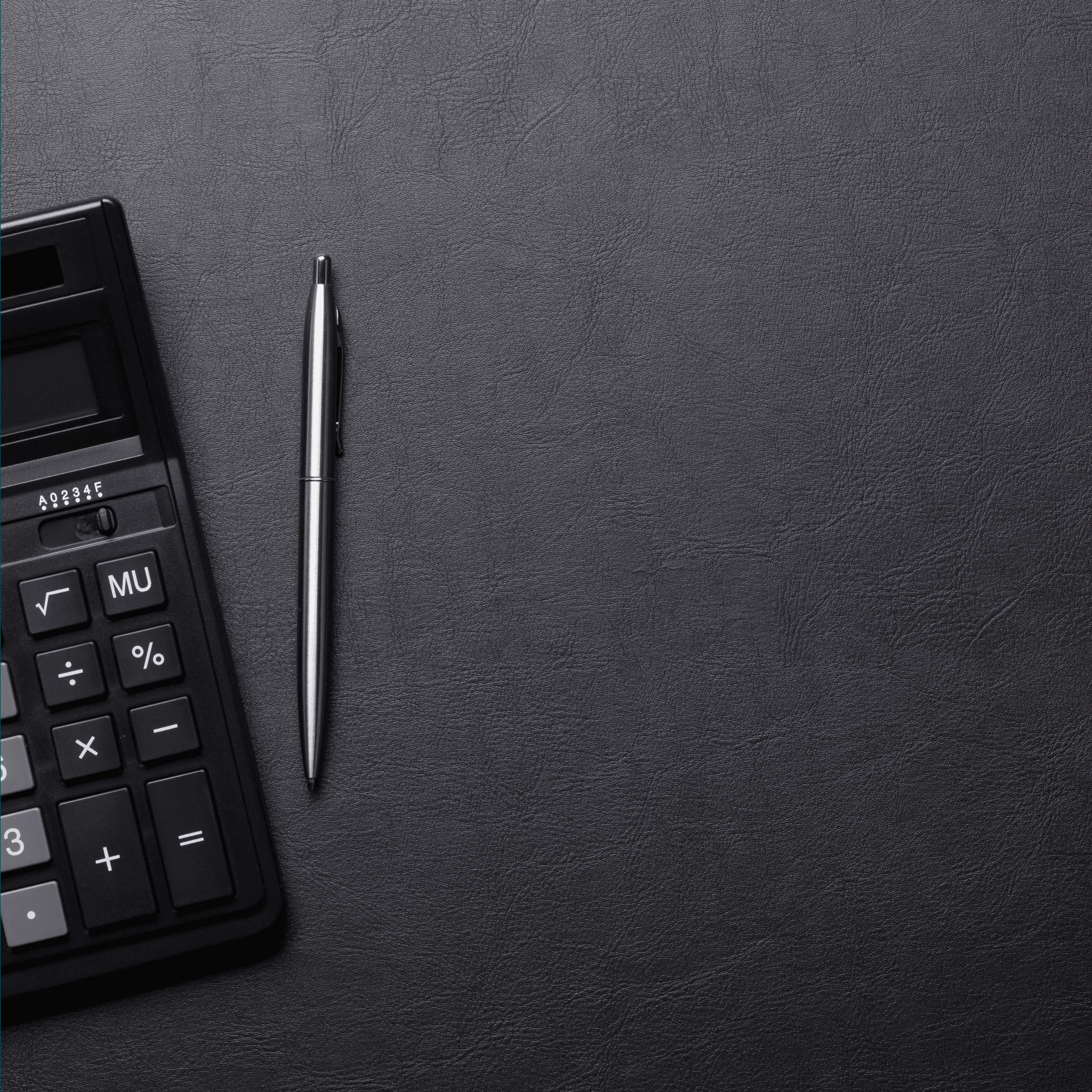 calculator and pen sitting on a desk